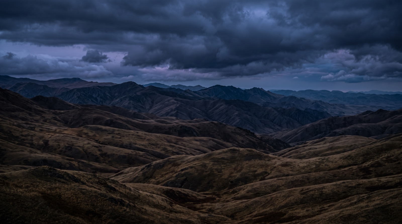 Grassland foothills under storm light